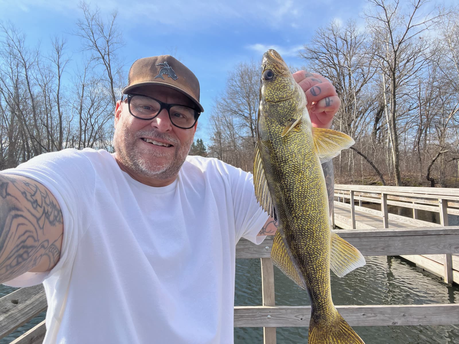An angler holding a walleye at the edge of a dock over open water